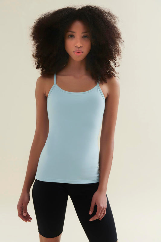 Woman wearing a light blue sustainable Pilates tank top and black yoga shorts made from sustainable, GOTS certified organic cotton and biodegradable elastane by Wellicious, perfect for eco-friendly activewear.